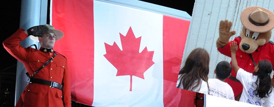 RCMP officer and Canada flag, Safety bear waving to children