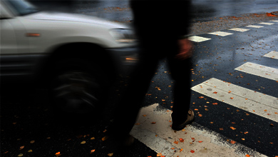 Piéton vêtu de noir qui traverse la rue