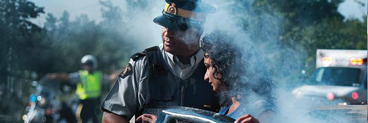 officer leading civilian away from smoke, ambulance and officer in background