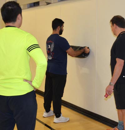 male lifting weigted object with two observers