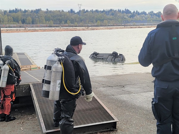 Un véhicule partiellement submergé est remorqué hors du fleuve Frasier sous le regard de deux plongeurs