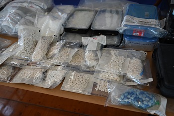 Dozens of bags and containers of various drugs laid out on a table.