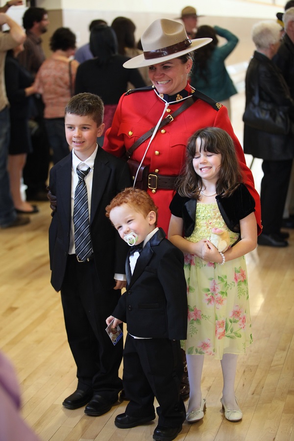 Cst. Mitchell standing in RCMP uniform with her three children