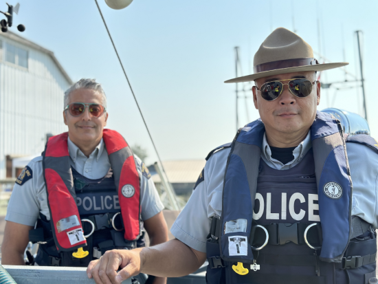 two police officers in a boat, wearing life jackets