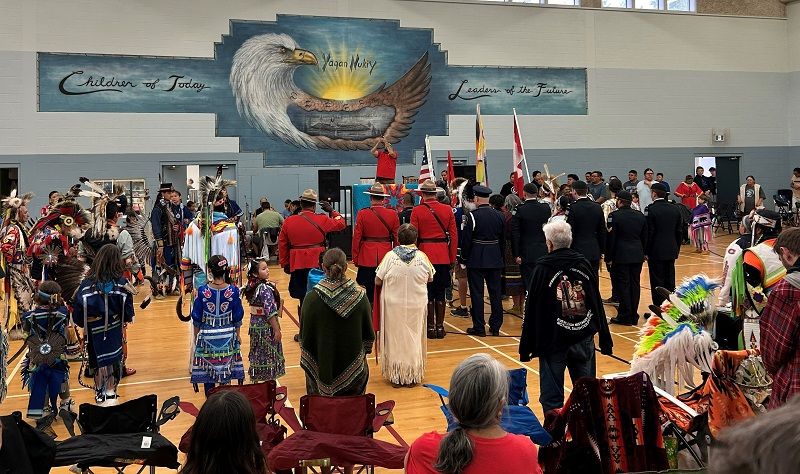 Indigenous dancers and mounties in red serge at the pow wow grand entry