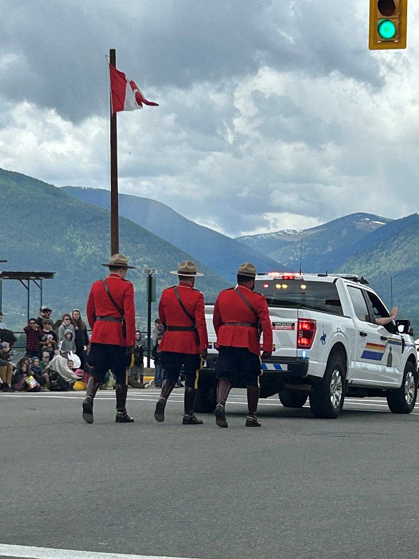 Officers in red serge marching behind a police car at a parade