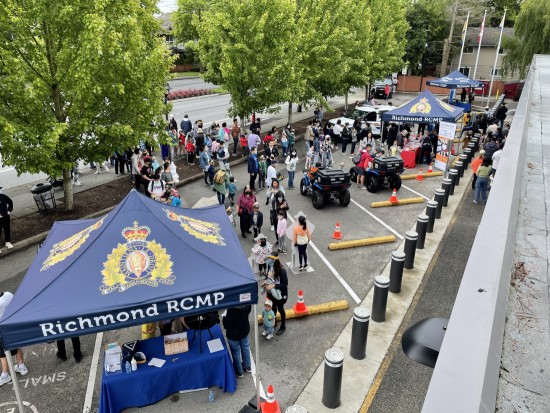 Vue aérienne du stationnement où sont installés des kiosques de la GRC de Richmond et où sont rassemblés des personnes, devant le bureau de police communautaire