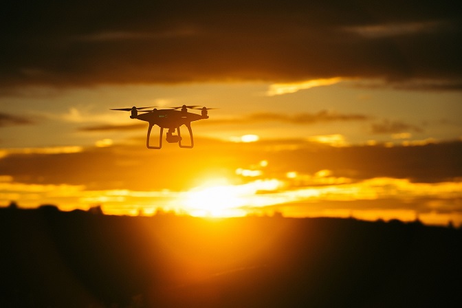 Photo d’un drone volant au coucher du soleil.