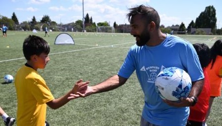 Des enfants souriant avec un ballon de soccer.