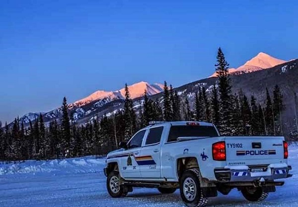 RCMP Pick up truck parked on a snowy road with snow-capped mountains in the background.