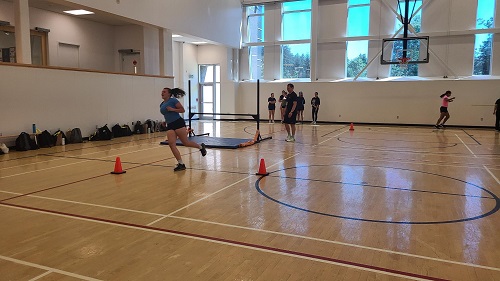 female youth running between pylons in an indoor gym