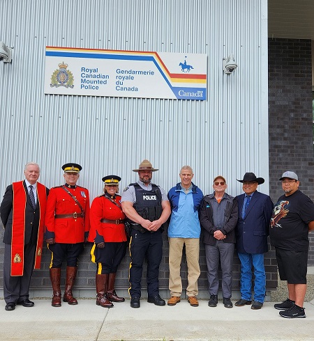 Group picture of VIPs and ceremony speakers with RCMP officers dress in ceremonial red serge.