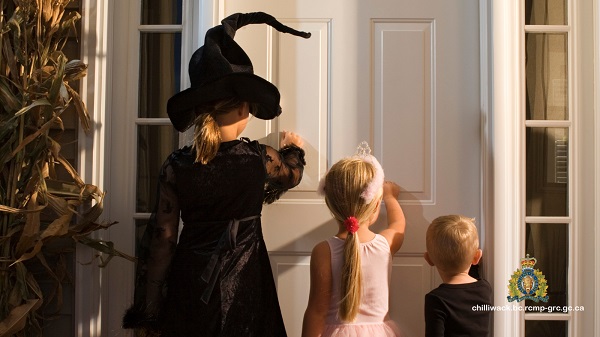 Three children knocking on a door dressed in Halloween costumes