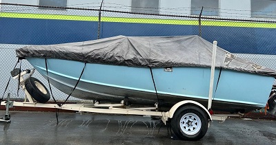 Blue boat with one engine on a boat trailer