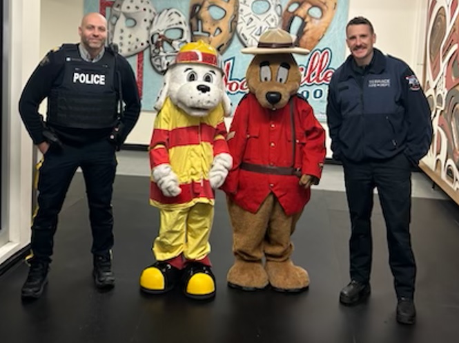 Standing from left to right: RCMP officer, Sparkie the Fire mascot, Safety Bear the RCMP mascot and Firefighter