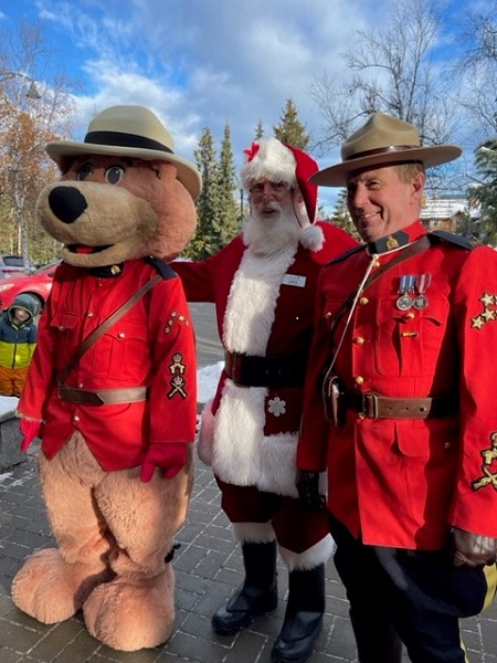 A photo of a RCMP police officer wearing the red serge, Santa Clause and Safety Bear in a red serge 