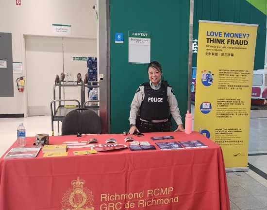 Richmond RCMP officer standing in front of fraud awareness booth inside a supermarket