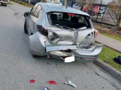 A parked car damaged by a tractor-trailer whose driver faces impaired driving charges