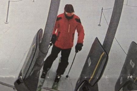 Photo de Thomasz Jaholkowski vêtu d’un manteau de ski rouge et noir ainsi que d’un pantalon de ski foncé et une tuque foncée. Il s’apprête à embarquer dans un remonte-pente.