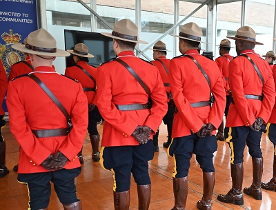 Photo de plusieurs membres de la GRC (vus de dos) portant la tunique rouge à l’intérieur