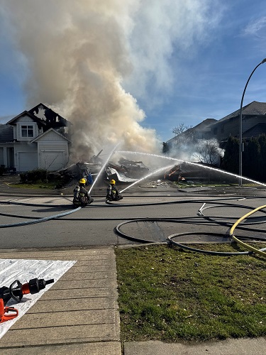 Photo of two firefighters and a burning house