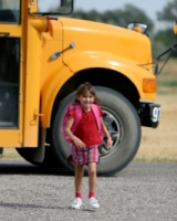 Child crossing the road beside a school bus