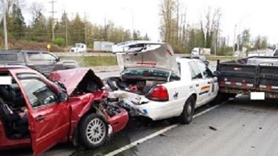 Damaged red car which rear ended a RCMP police cruiser on the side of the road