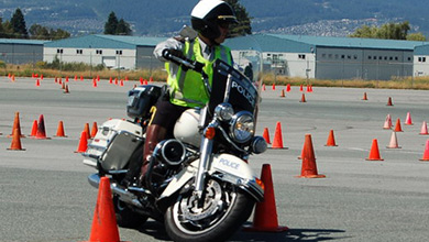 Un agent contourne des cônes de signalisation sur une motocyclette.