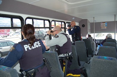 Trois agents dans un autobus municipal surveillent les voitures qui passent au cas où certains conducteurs seraient inattentifs