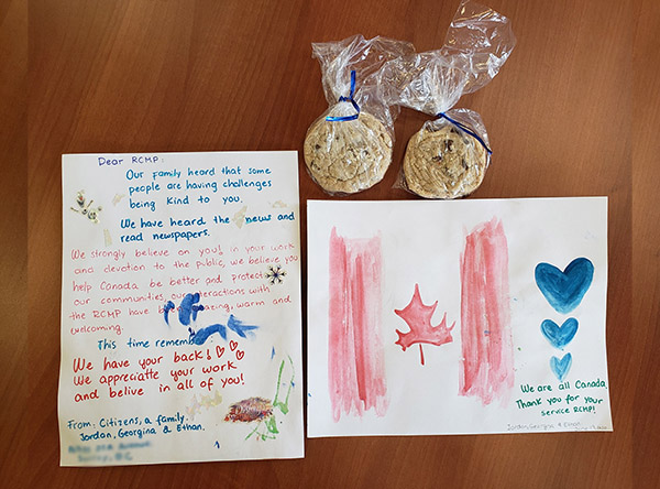 A letter and card with two bags of homemade cookies. One card has painting of the Canada flag and  three blue hearts beside it.