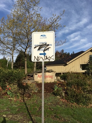picture of sign with "vax" spray painted on it