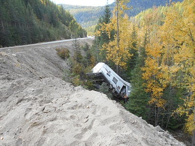 Photo of truck and trailer down an embankment.