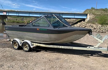 16 foot Outlaw river boat on an EZ loader trailer, two tone grey with orange and green writing