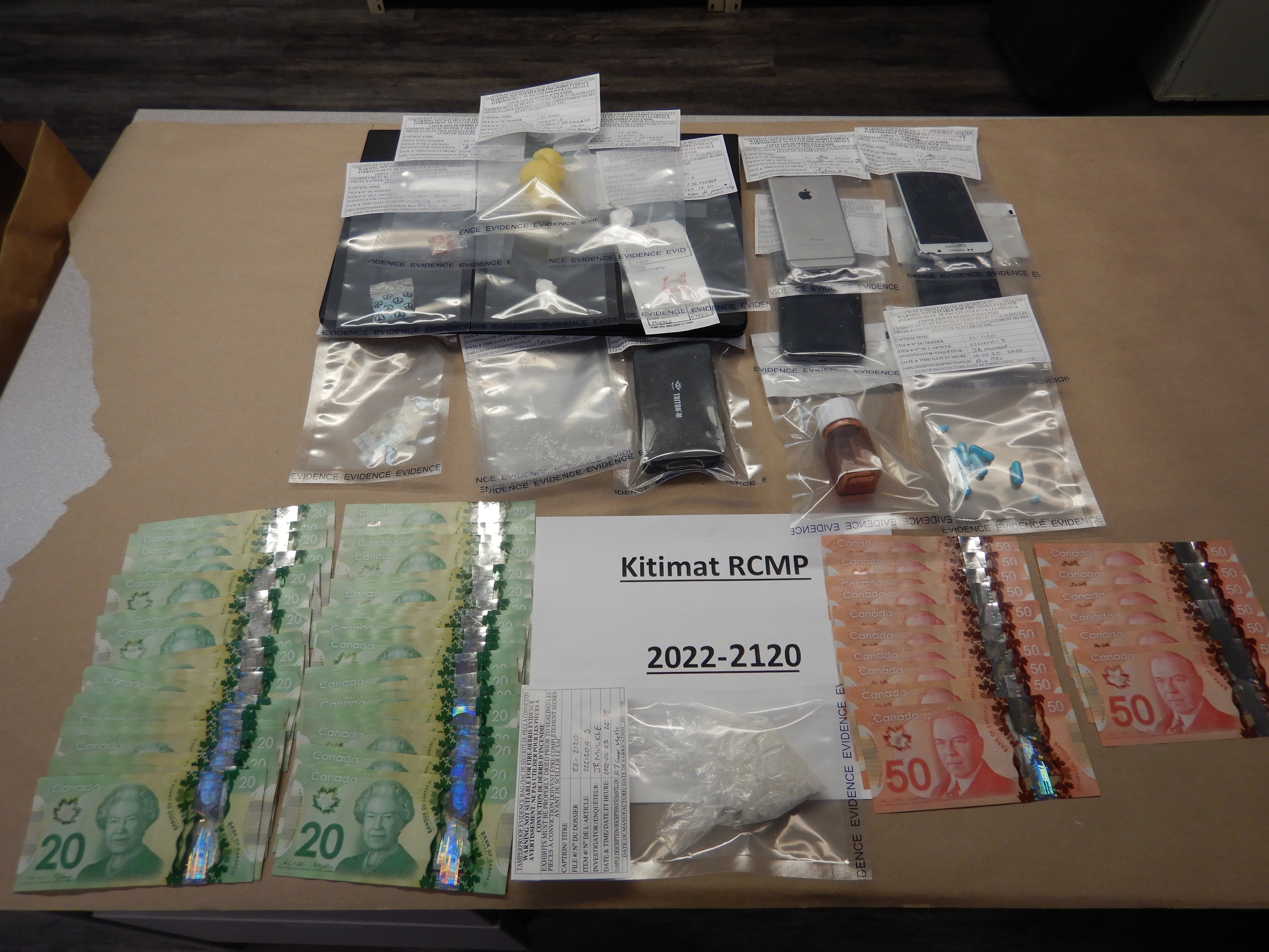Photo of cash, phones and plastic bags with drugs. Text reads Kitimat RCMP 2022-2120