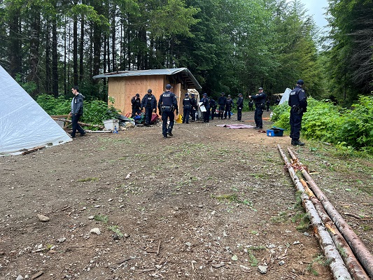 Photo of police officers dismantling a building structure in the protest camp