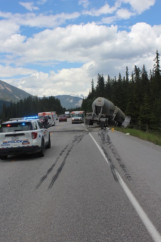 Collision scene on Hwy 1 with semi in eastbound ditch and emergency crews on roadway.