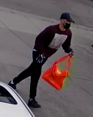  Suspect de la fusillade, le visage couvert, portant des gants et transportant un sac rouge 