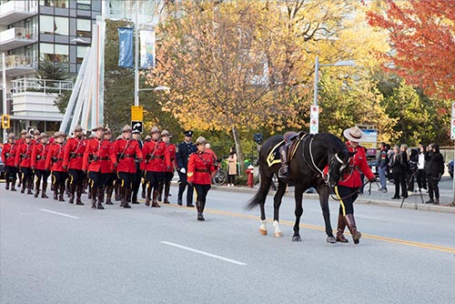 Un cheval non monté et des membres vêtus de la tunique rouge en train de marcher.