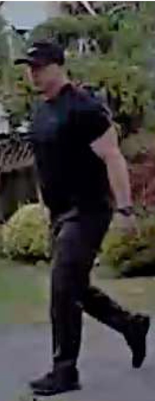 Left side view of a man wearing a black hat, black short sleeved t-shirt, black pants and black shoes.