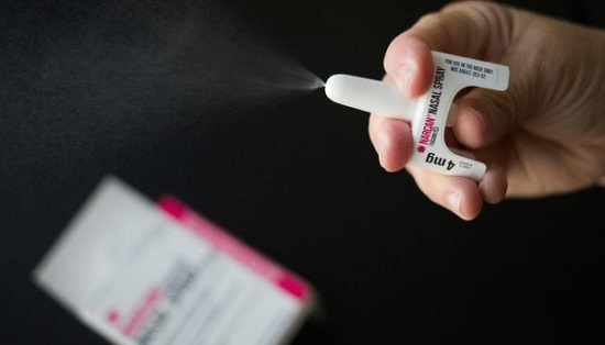 photo of naloxone nasal spray discharging over black background