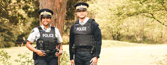 Two officers in uniform standing by a tree