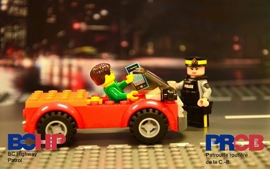 Voiture en Lego avec conducteur tenant un téléphone, agent de la GRC en Lego debout près de la voiture
