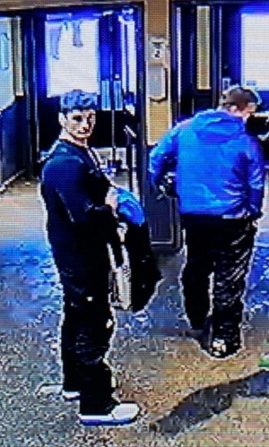 ): two suspects standing together in a doorway. One wearing all black and the other wearing a blue jacket.