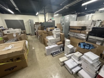A wide photo of a large room packed with stacked boxes