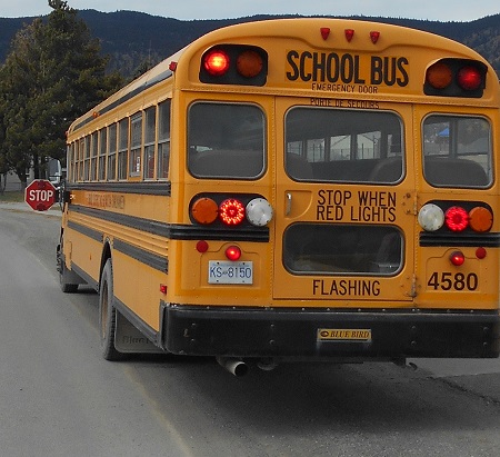 School bus with flashing lights activated and stop sign displayed. 