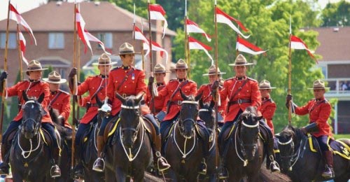 Mounties, including Cpl. Kyle Kifferling, riding horses and holding red and white lances during an outdoor performance of the Musical Ride  