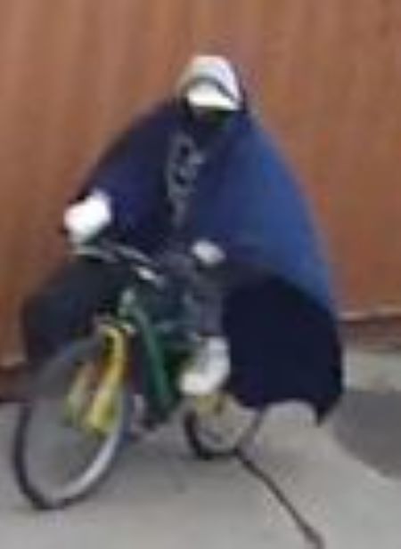 Le suspect à vélo : Un suspect porte une couverture bleue autour des épaules comme une cape et conduit un vélo jaune et vert. 
