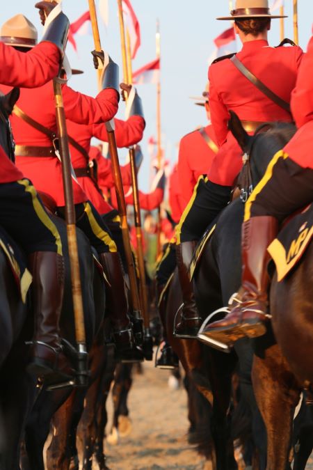 Légende de la photo : Deux colonnes de gendarmes à cheval vêtus de leurs tuniques rouges.