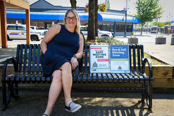 a Ridge Meadows RCMP municipal employee holding both buy and sell safe zone signs