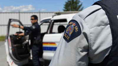 A police officer standing near a police vehicle as a training officer provides instructions.